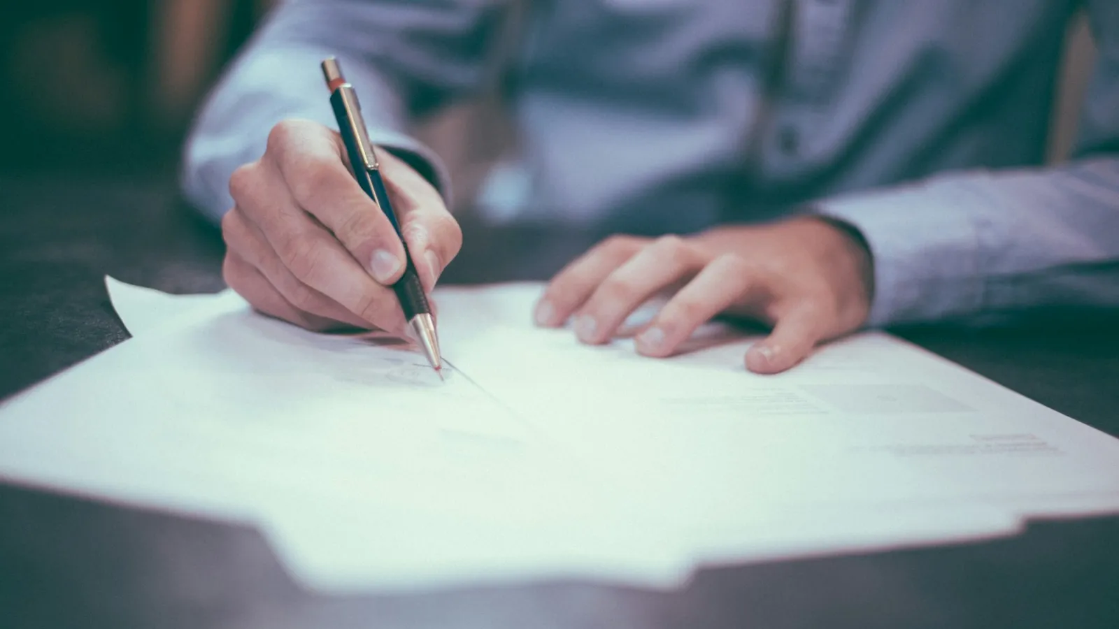 Persona revisando y firmando documentación sobre una mesa