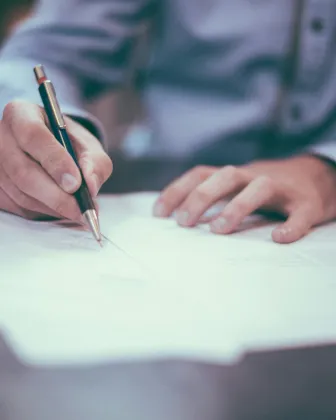 Persona revisando y firmando documentación sobre una mesa