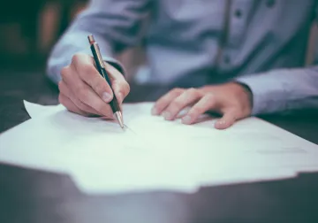 Persona revisando y firmando documentación sobre una mesa