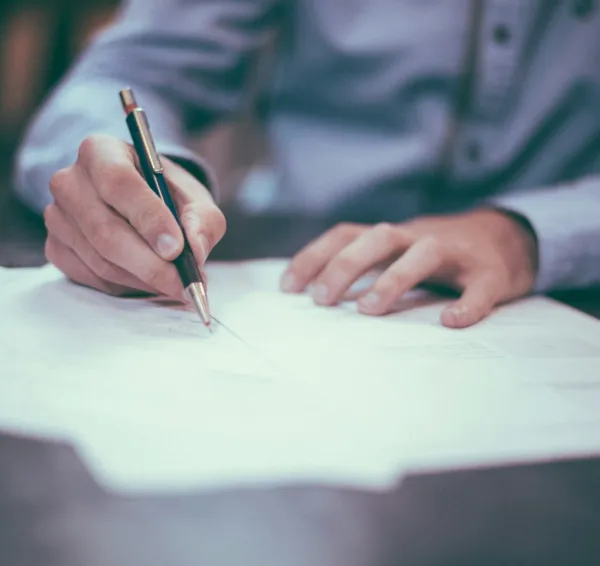 Persona revisando y firmando documentación sobre una mesa